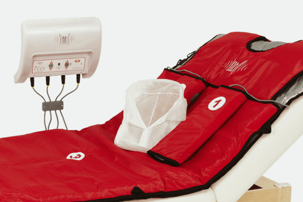 FIT Bodywrap system setup with red infrared heat therapy wrap on a spa treatment bed, designed for body detox and relaxation.