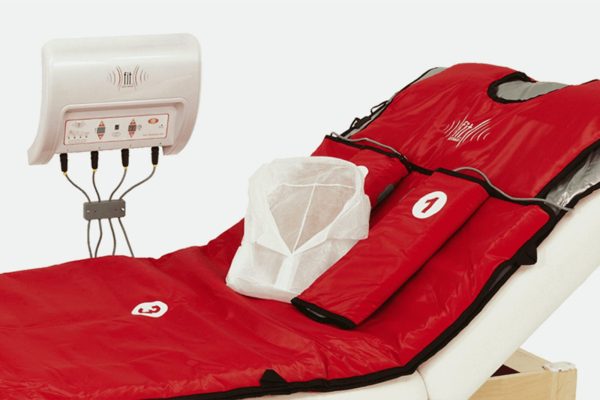 FIT Bodywrap system setup with red infrared heat therapy wrap on a spa treatment bed, designed for body detox and relaxation.